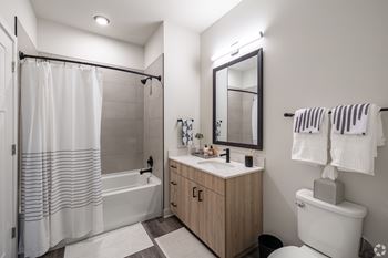 A white bathroom with a wooden cabinet and a white toilet.